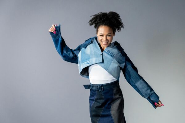 Joyful model with afro hair in a trendy denim ensemble. Studio setup.